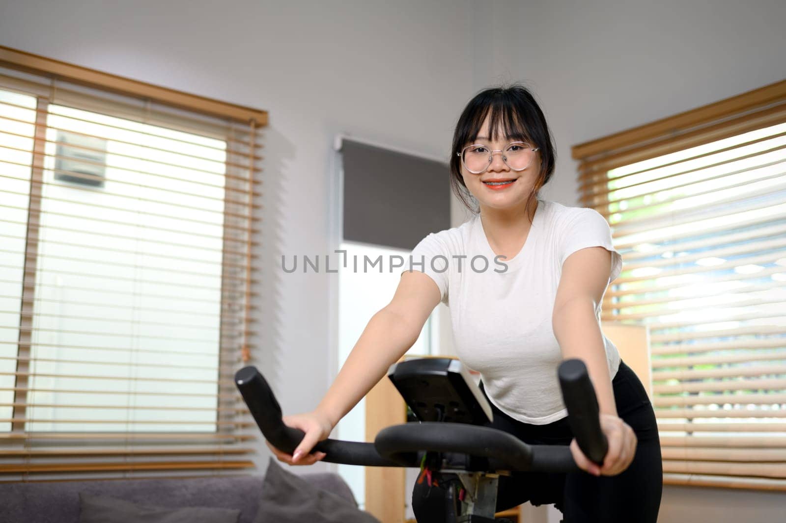 Young woman doing cardio workout on stationary bike at home.