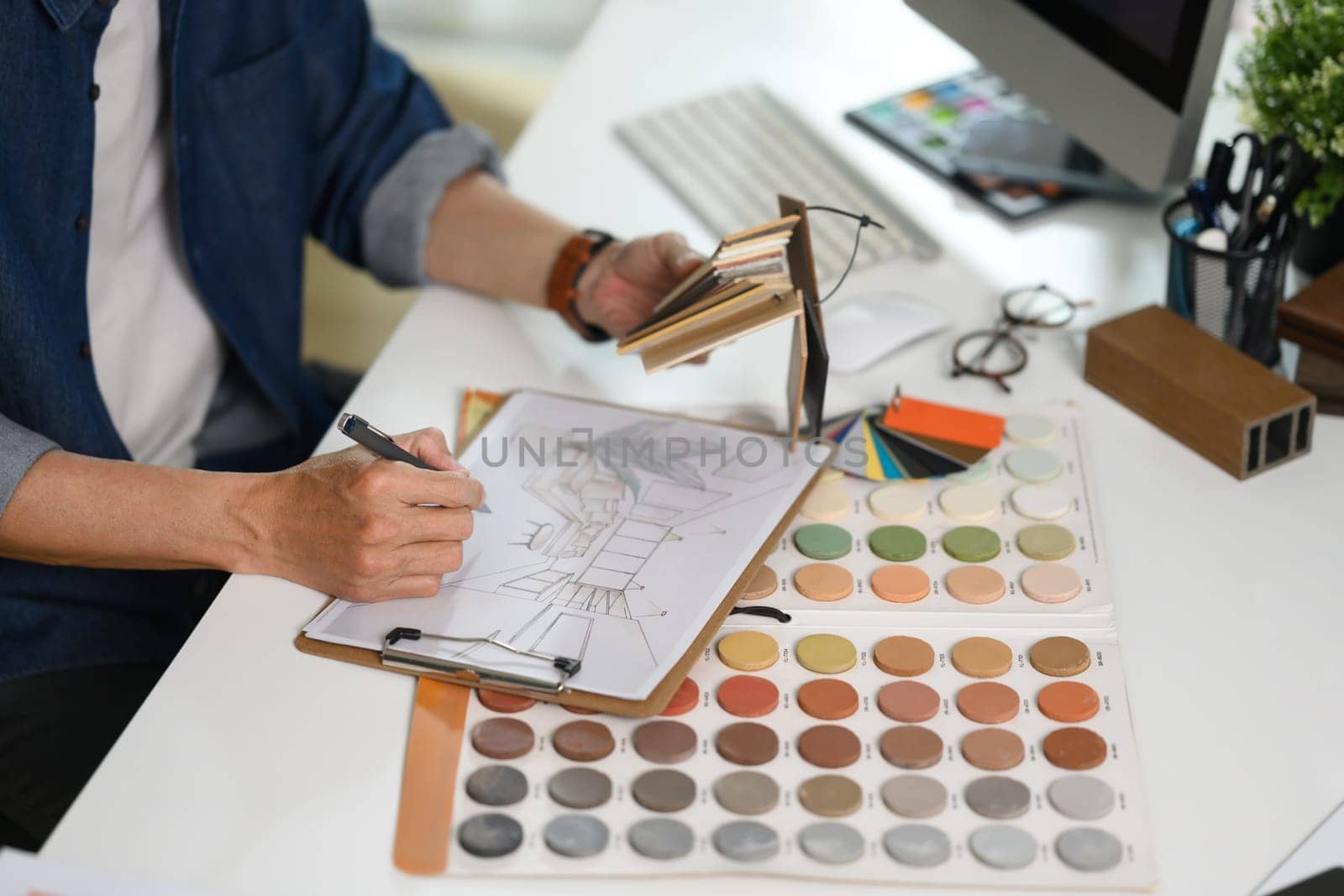 Experienced interior designer working with material and color samples at his workplace.