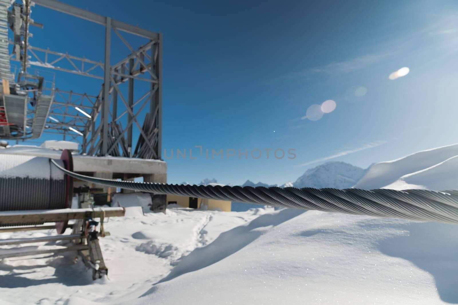 A cable car station high in the mountains under construction. Snowy mountain landscape and construction of a metal structure for a cable car.