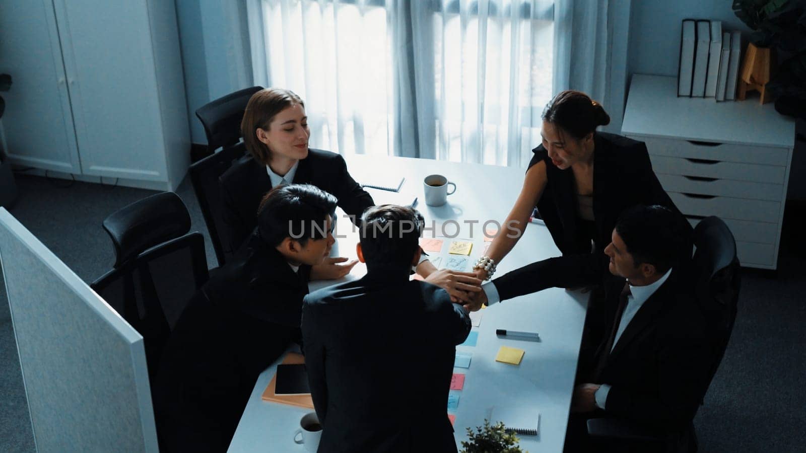 Top view of professional project manager present idea while diverse team putting hands together and clapping hand to celebrate successful strategy at meeting room. Show unity, teamwork. Directorate.