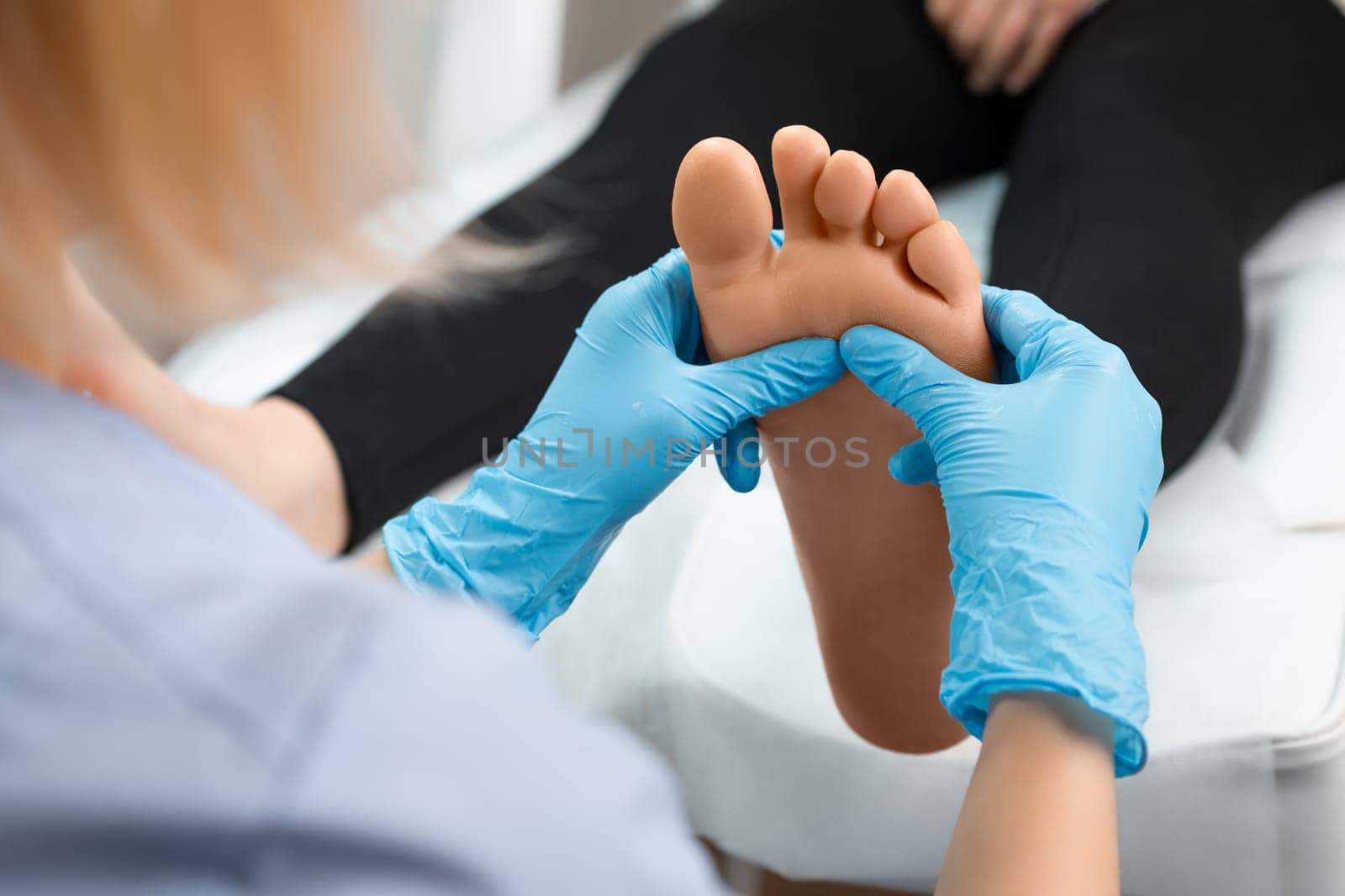 Close up of masseur doing foot reflexology massage to woman at beauty salon by vladimka