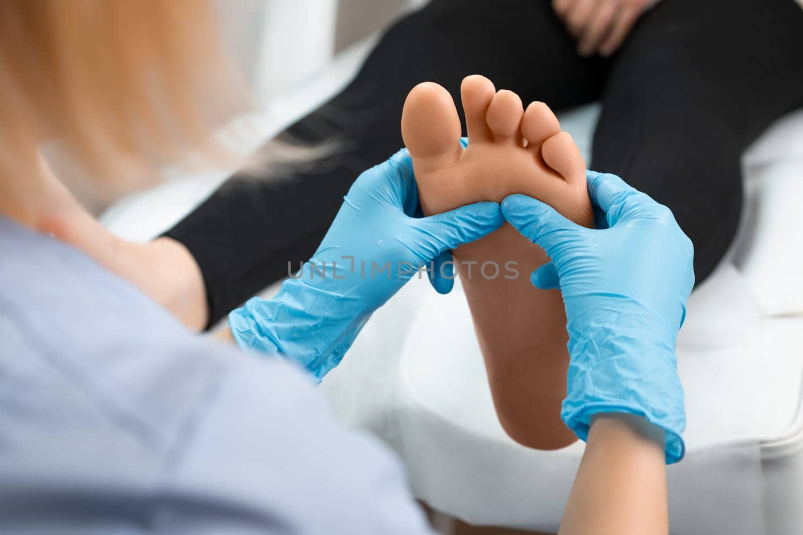 Close up of masseur doing foot reflexology massage to woman at beauty salon.