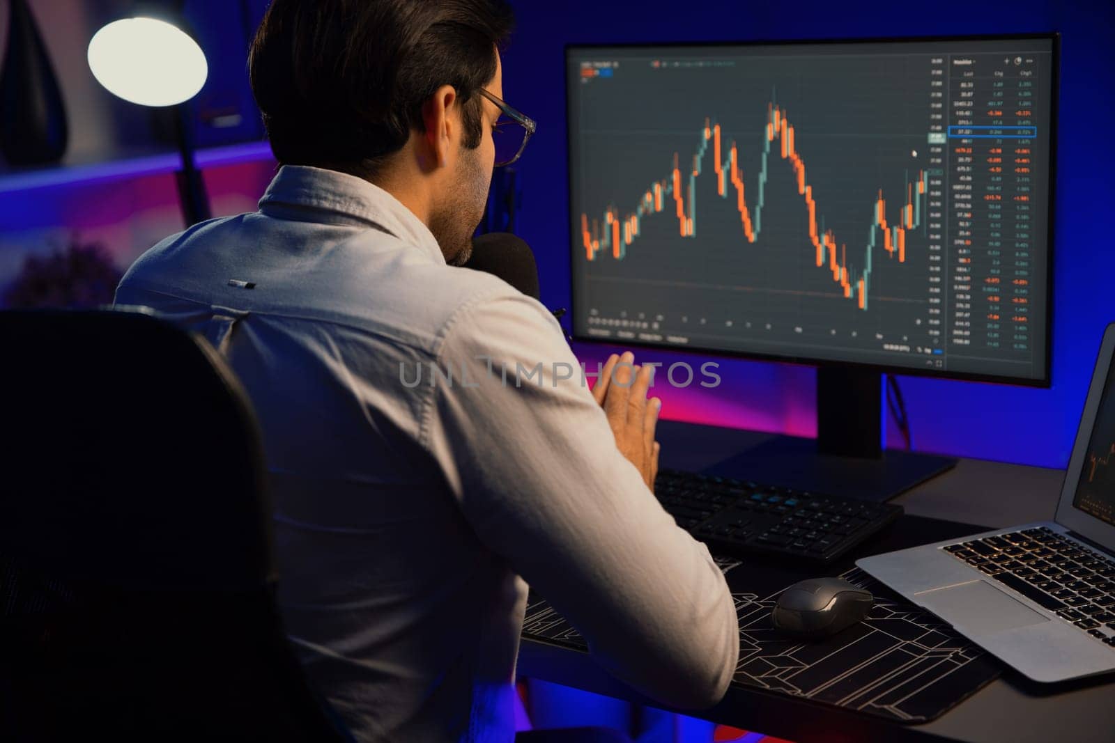 Smart trader businessman concentrating on dynamic stock exchange investment on pc and laptop showing on screen with high profit in searching market at neon light office in dark room night. Surmise.