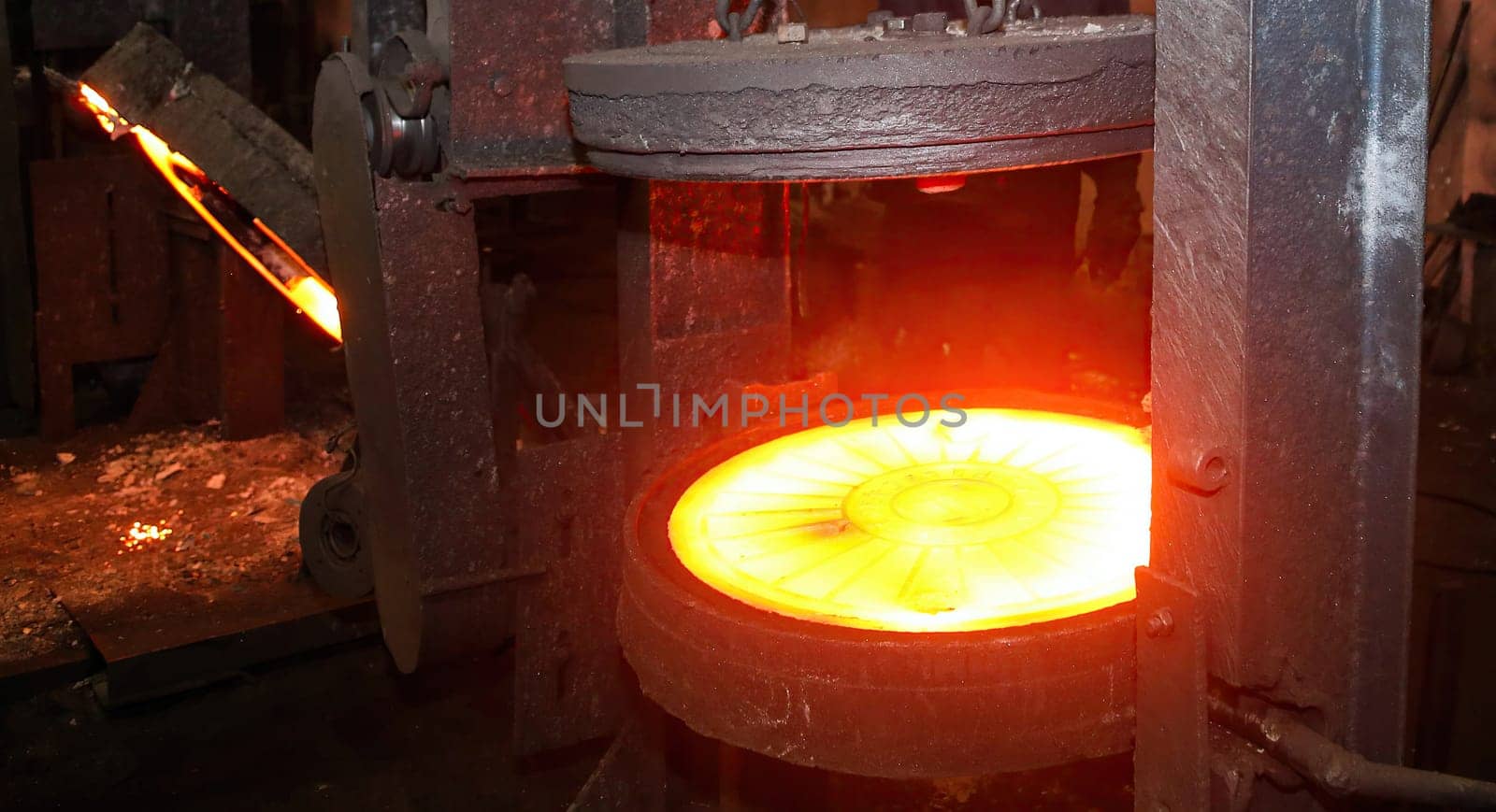 Industrial metalworking or manufacturing concept. Glowing hot round metal disc forging press isolated on black background. Industrial concept of power, energy, and strength.