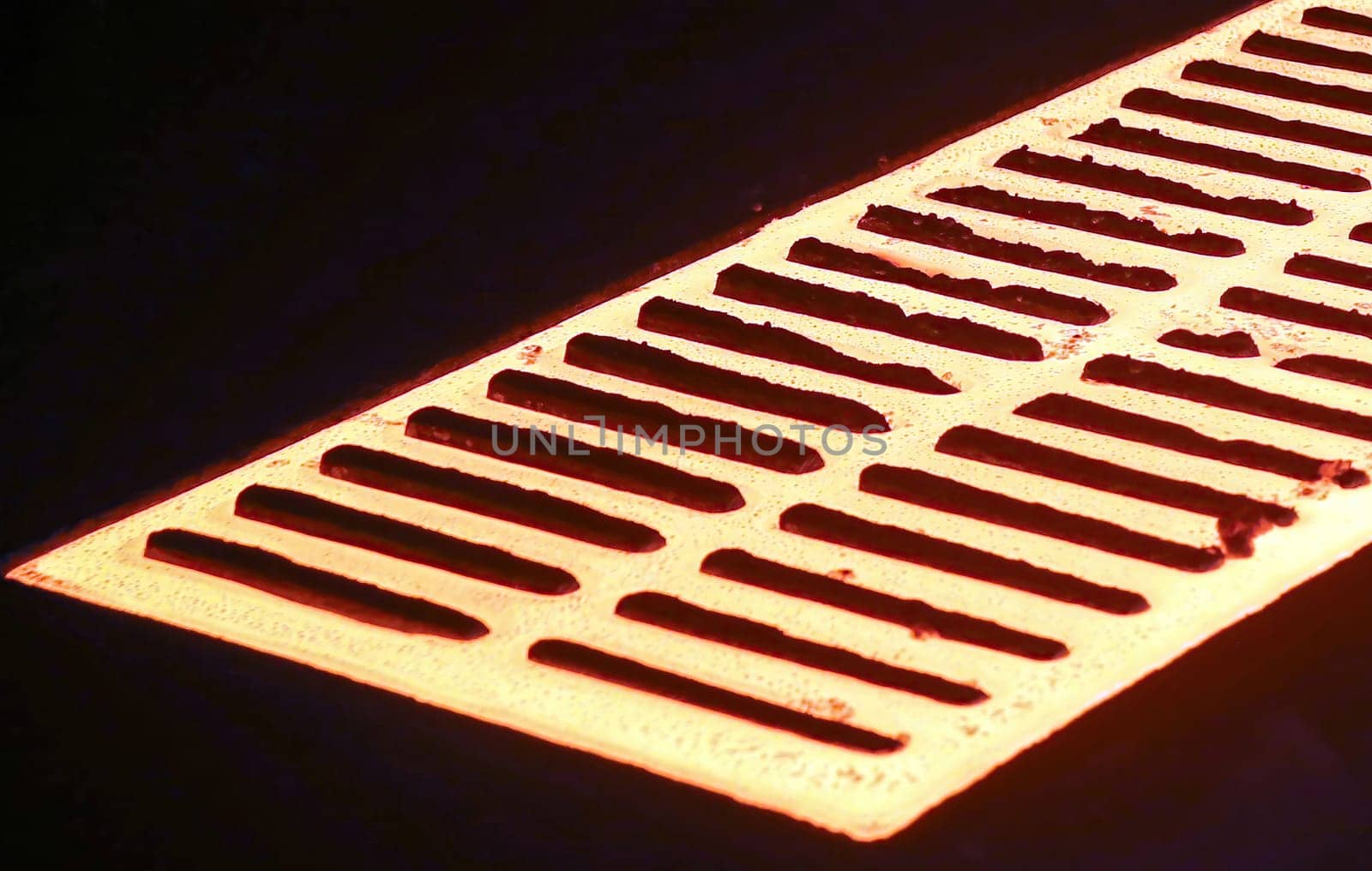 Molten metal poured from ladle into mold to make casting. Metal glows brightly, flows into mold, sparks fly as metal hits mold, on dark background, showcasing metal casting process.