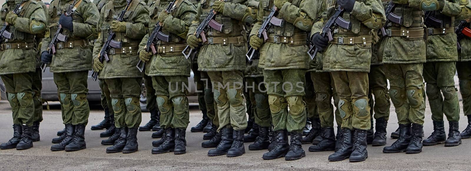 Disciplined soldiers in camouflage march in perfect synchronization during a military parade. Helmets and rifles add to the display of unity and strength, evoking pride.