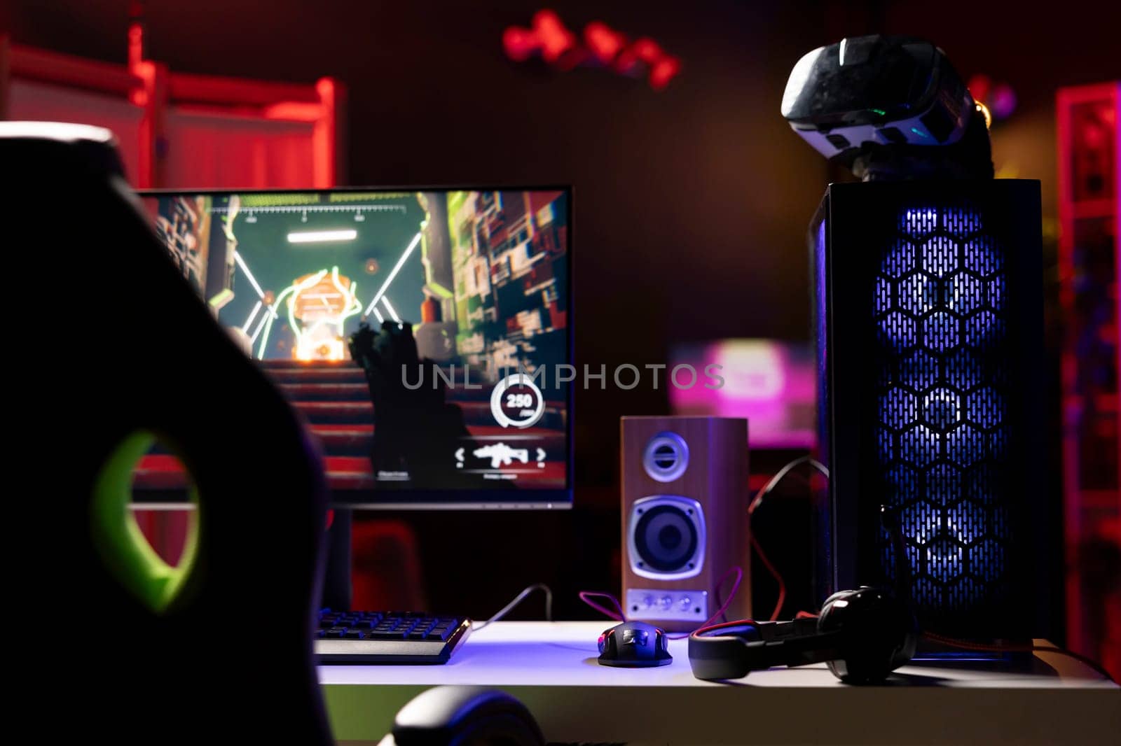 Professional gaming empty room studio with neon lights and RGB lit computer next to headphones and VR headset. FPS videogame on pc display and virtual reality goggles in apartment