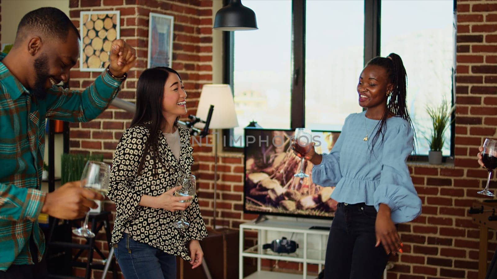 Multiethnic school colleagues celebrating summer vacation, organizing apartment party, enthusiastically dancing. Happy group of friends enjoying time spent together, busting into energetic dance moves
