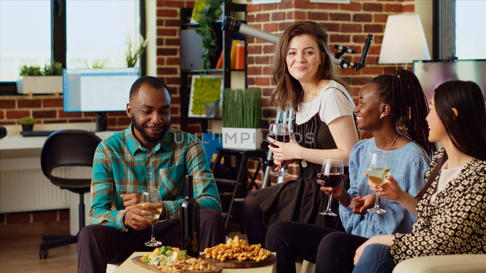 Portrait of happy friends having entertaining conversation, eating snacks from charcuterie board at home. Cheerful african american, asian and caucasian people throwing party in cozy apartment