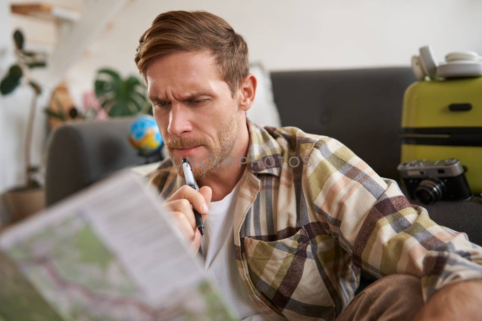 Man with serious face thinking, looking at travel map, planning vacation, going on holiday. Travelling concept
