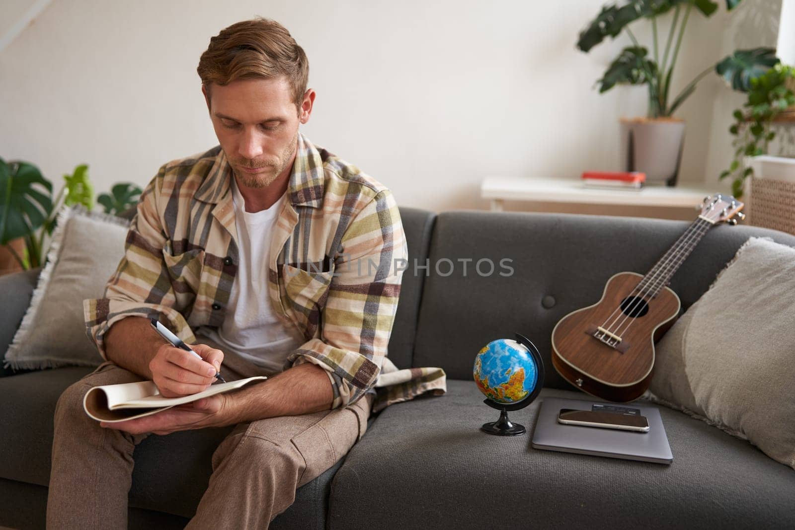 Portrait of man, tourist makes plans for his next vacation, writing a list of things to take with him, making a check-list.