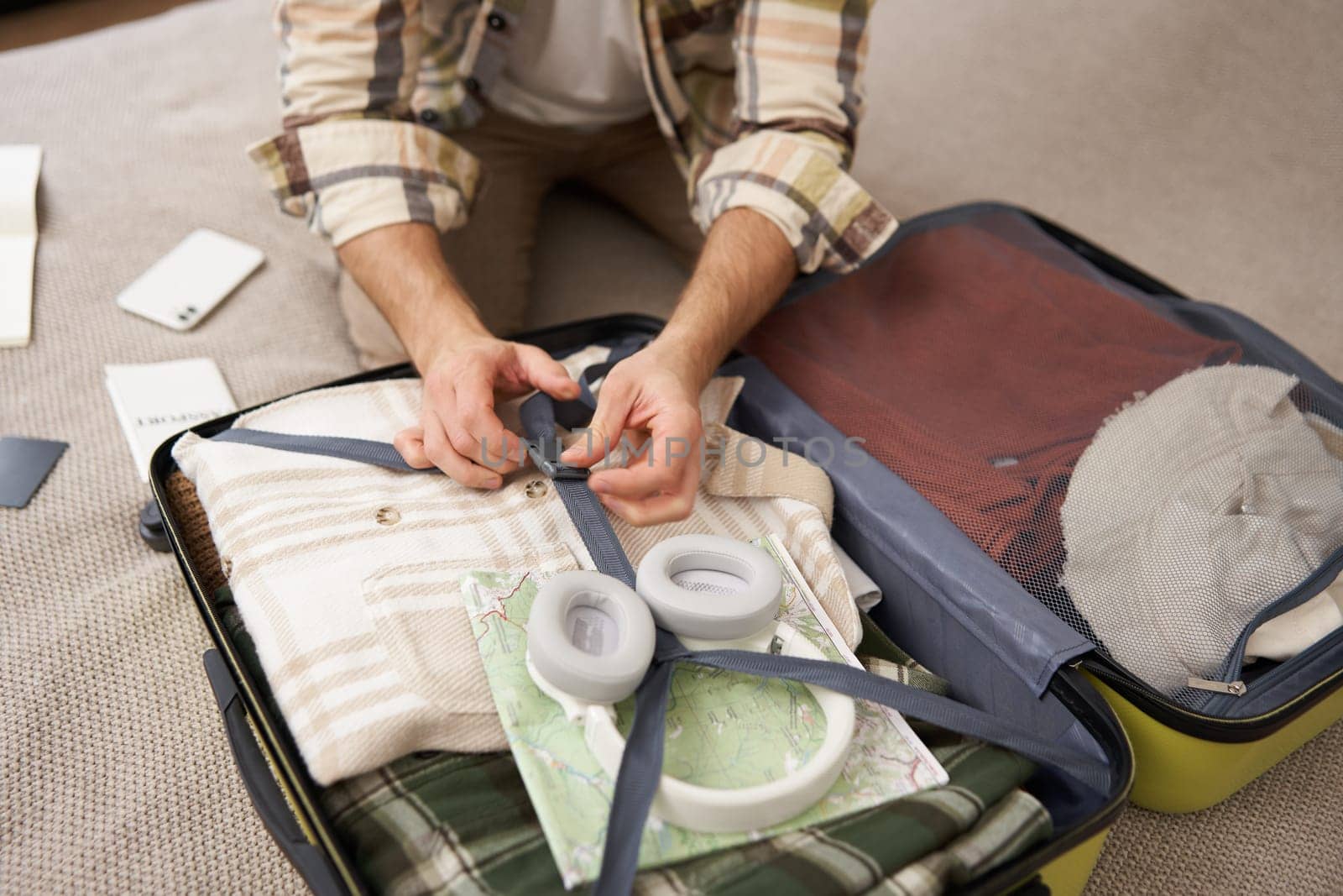 Close up portrait of male hands, man putting clothes inside suitcase, packing for holiday. Tourism and travelling concept