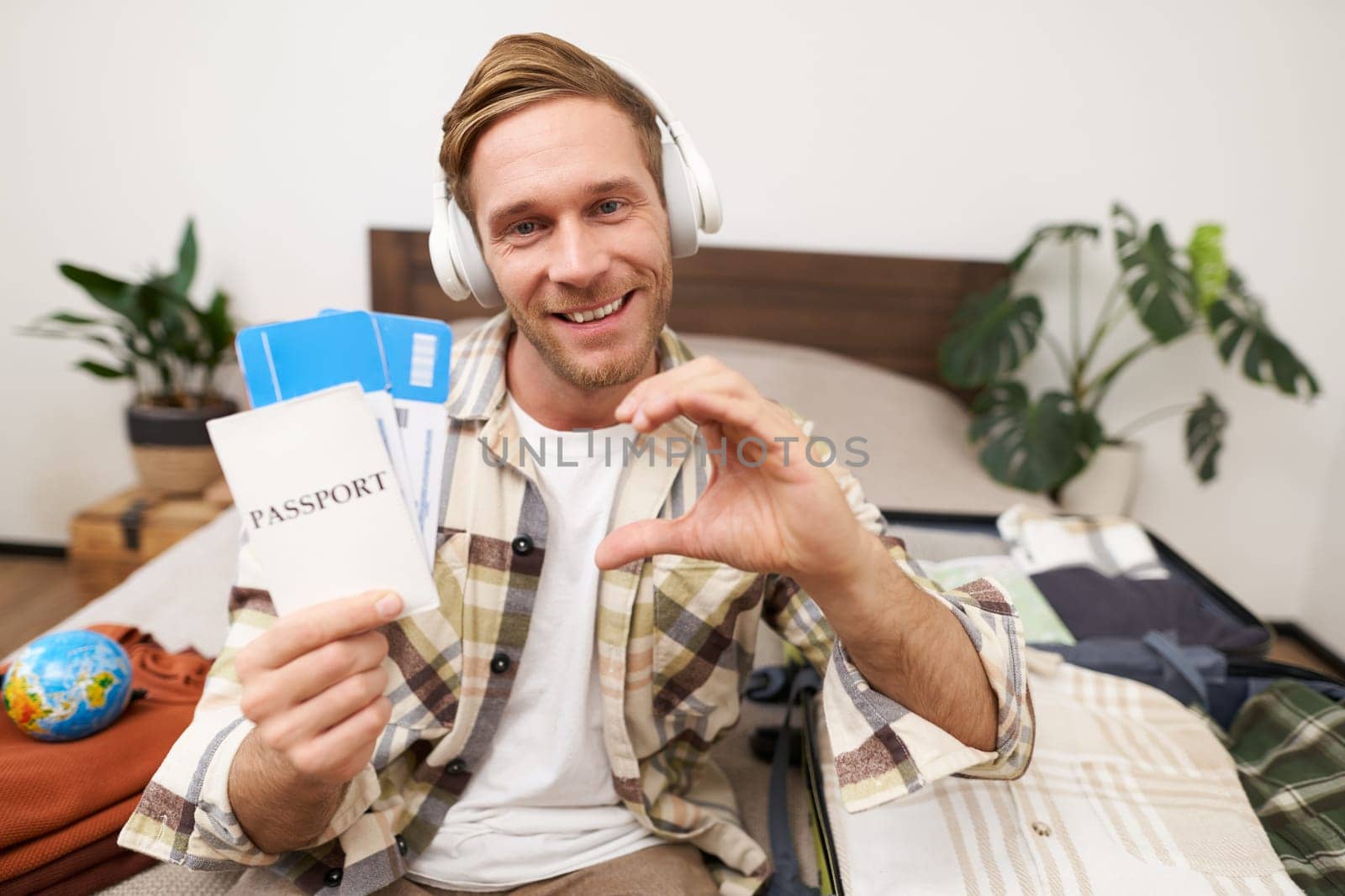 Portrait of smiling man, tourist shows two tickets and passport, goes on holiday, traveller like travel agency.