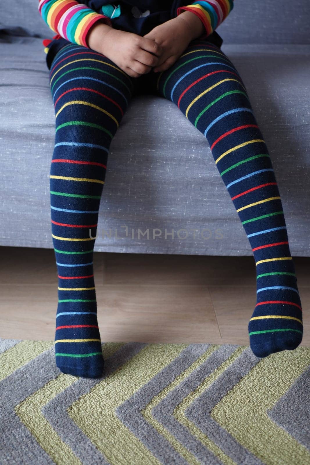 child with Colorful striped socks sitting on sofa ,