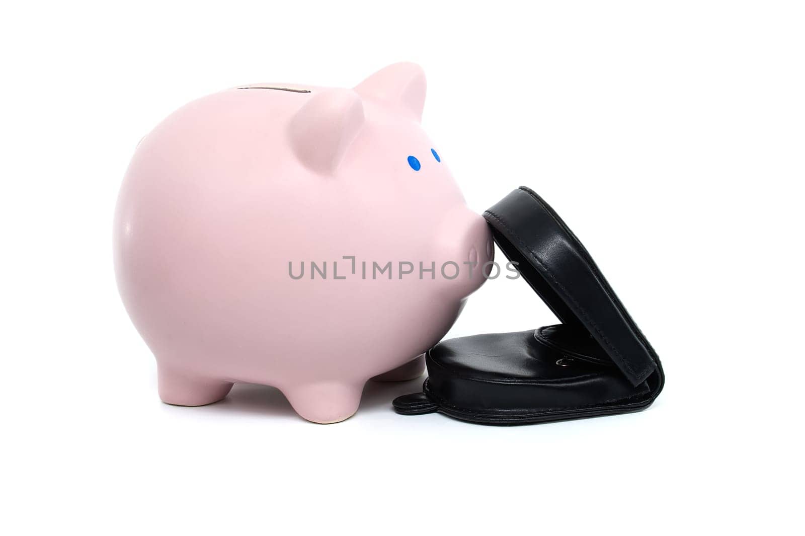 Pink piggy bank alongside a black wallet which is open showing some bills, isolated on a white background