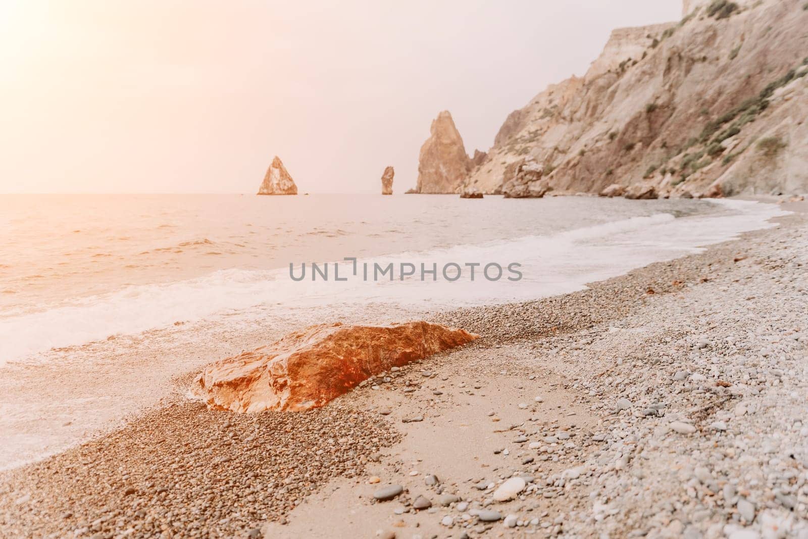 Large red jasper rock on the beach, with the sea in the background. Big Red Jasper Stone Close Up by panophotograph