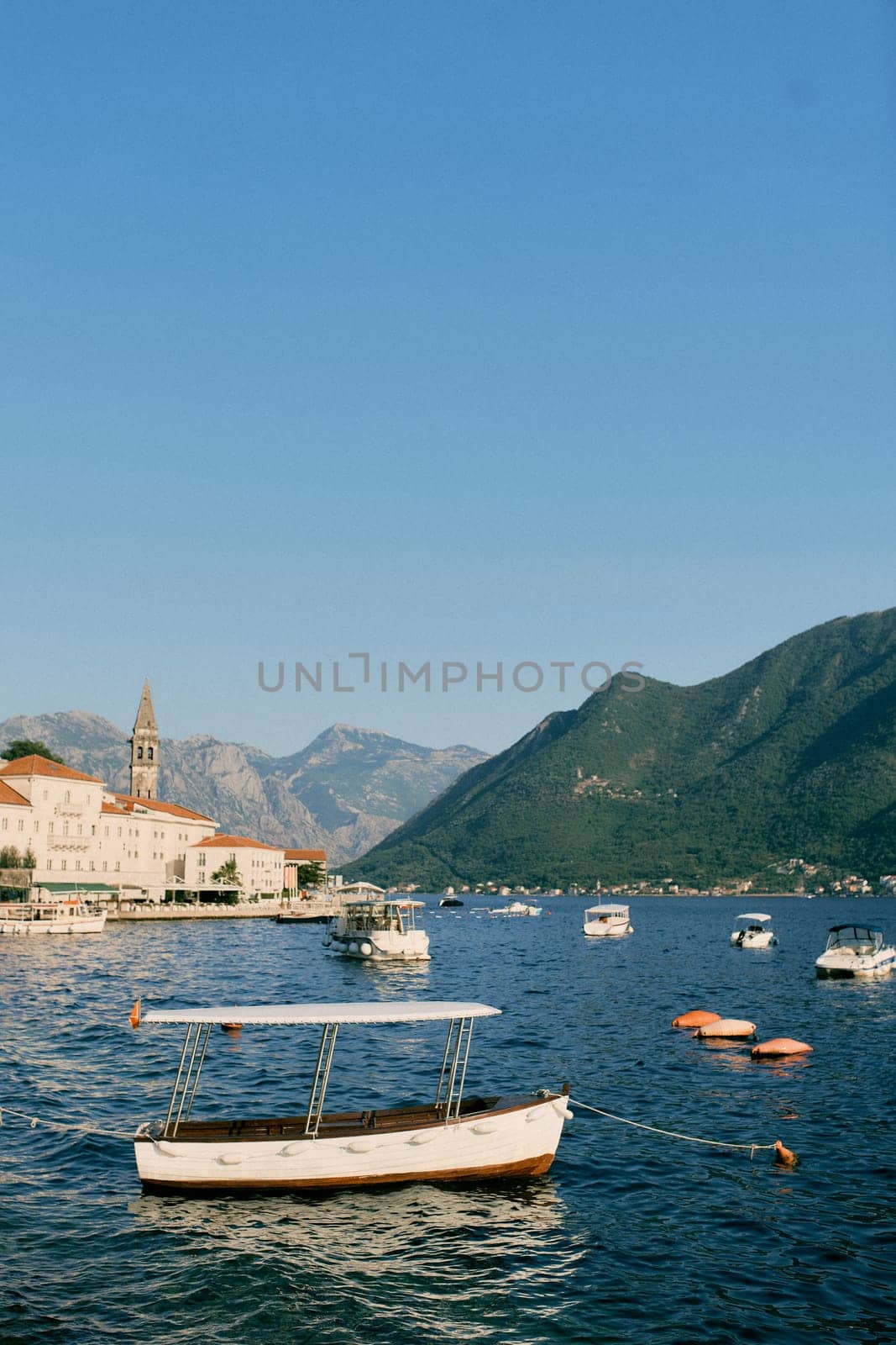 Small excursion boats are moored in the sea off the coast of Perast. Montenegro by Nadtochiy