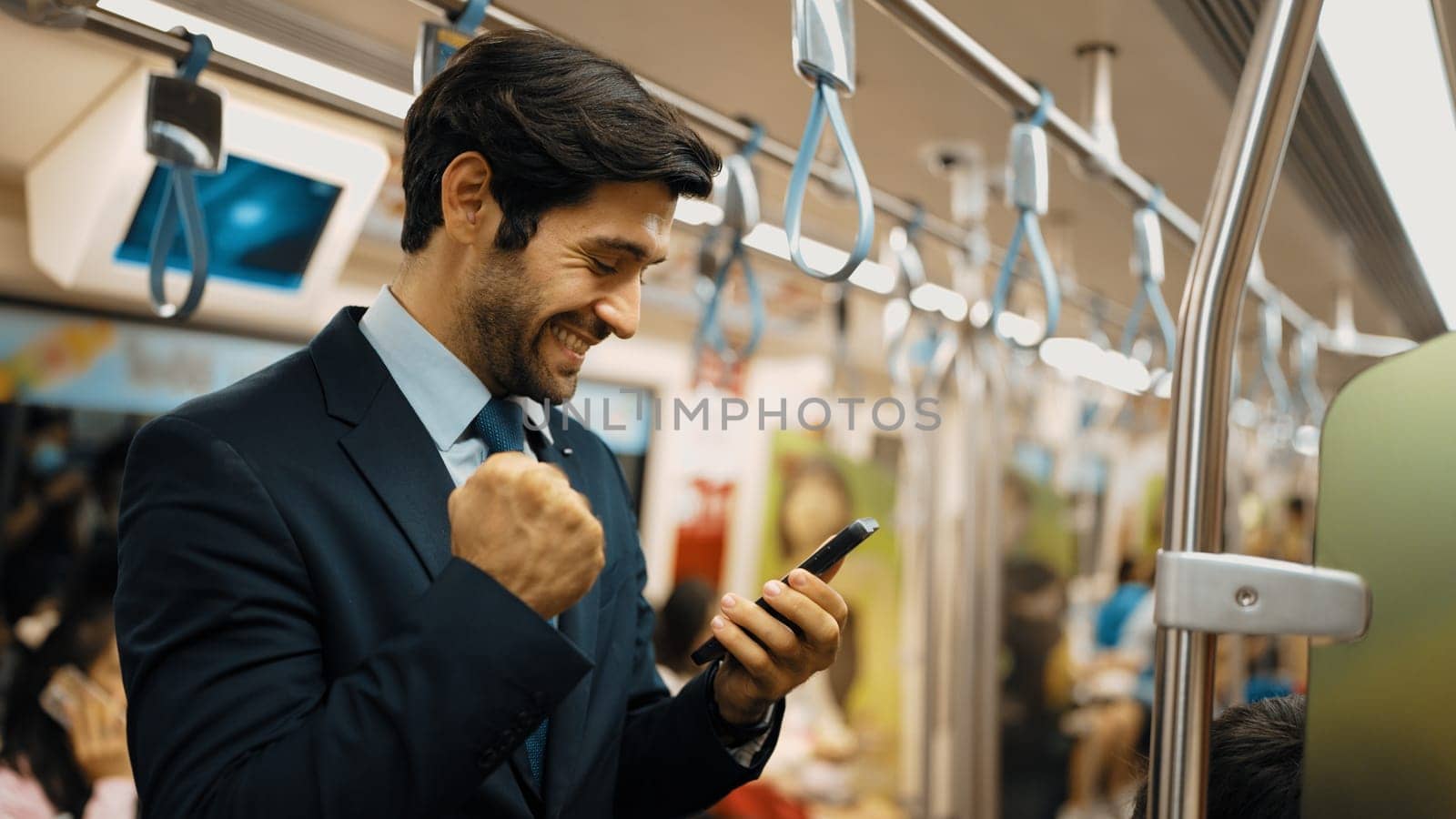 Professional business man celebrate for getting promotion while standing in train. Caucasian male ,leader looking at phone while receive good news about successful project, increasing sales. Exultant.
