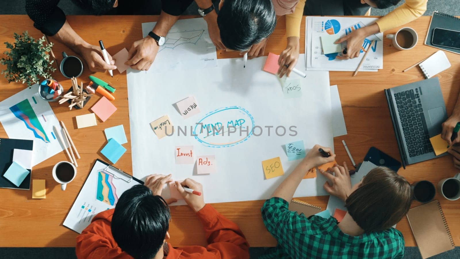 Group of business people writing and making mind map to brainstorming marketing idea at meeting. Top aerial view of investors sharing plan or strategy by using sticky notes. Top view. Convocation.