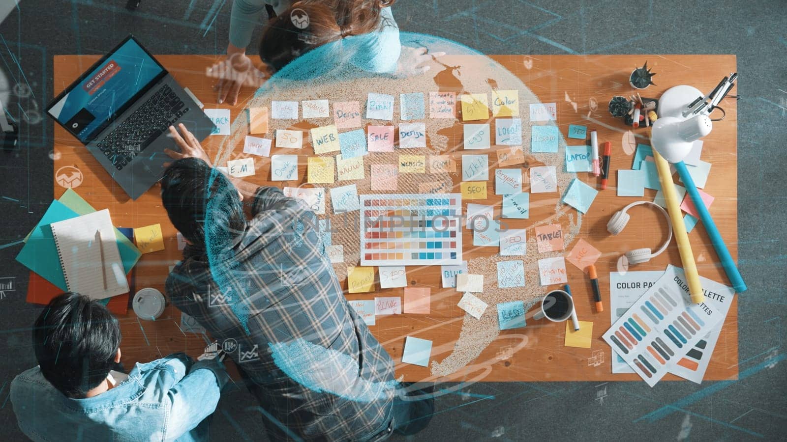 Top down view of business team with casual outfit looking laptop screen and sharing idea. Aerial view of manager works and checking color palette at table with global network holographic. Symposium.