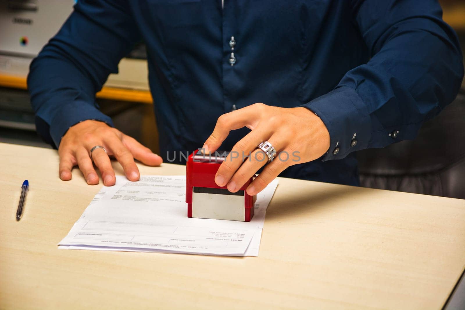 A man putting a stamp on a piece of paper. Photo of a man stamping a document
