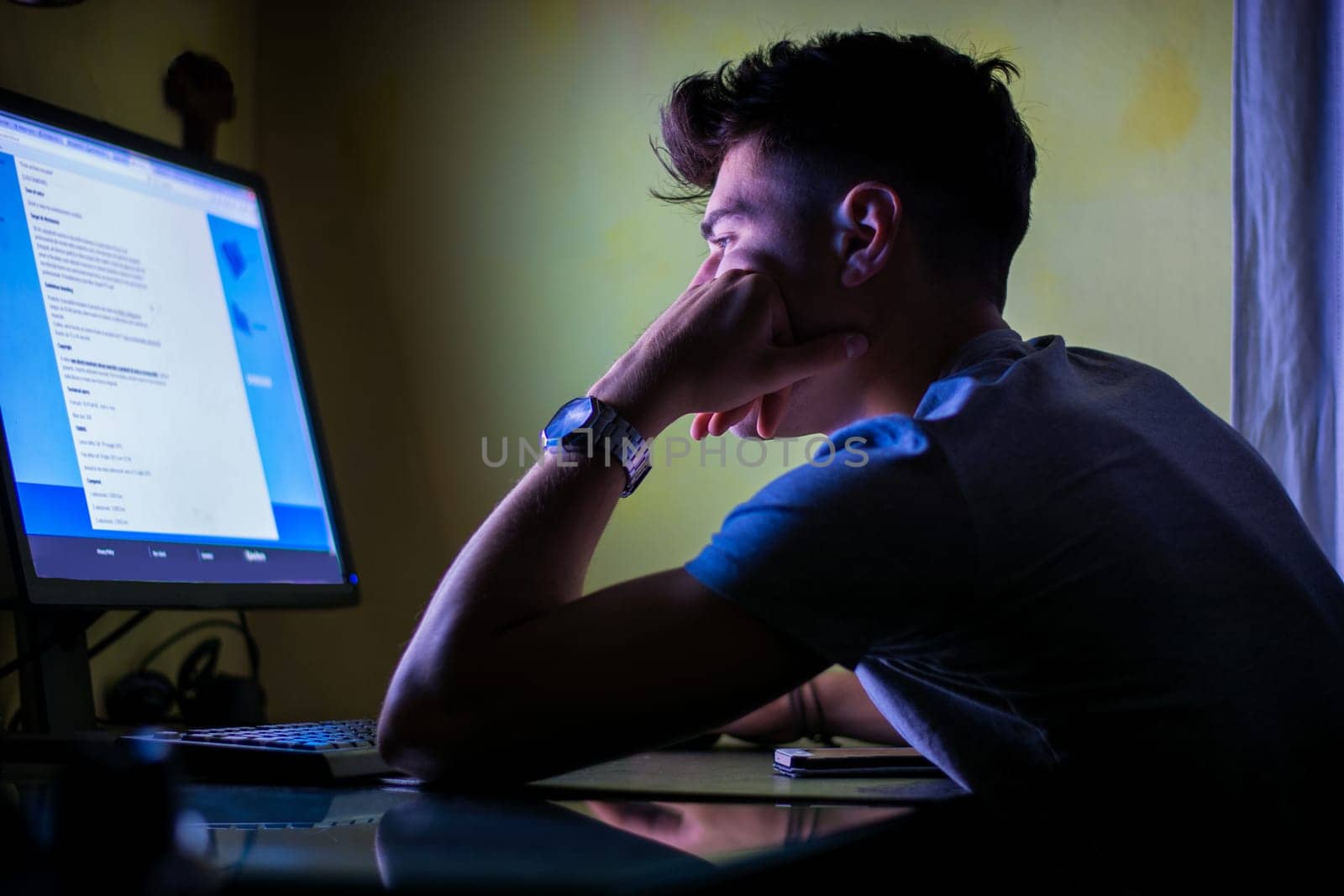 A man sitting at a desk in front of a computer. Photo of a man working at a desk with a computer