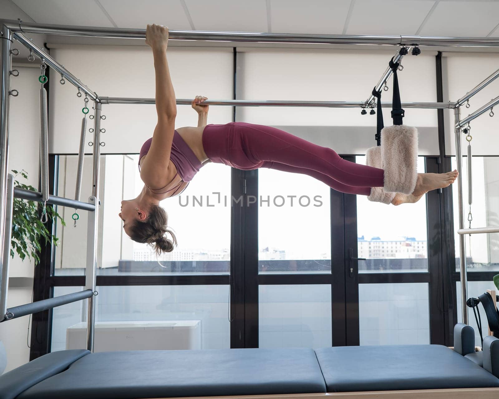 A caucasian woman is engaged in Pilates on a reformer simulator. Hanging position. by mrwed54