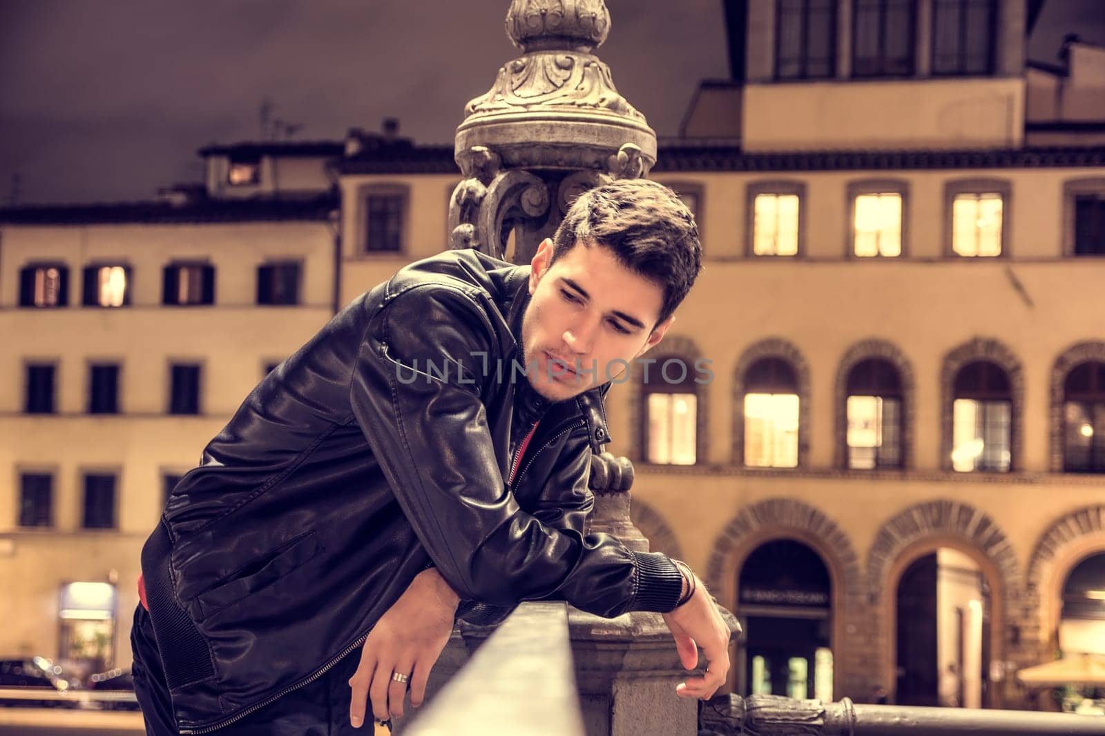 A man leaning on a railing in front of a building. Photo of a man leaning on a railing in front of a building