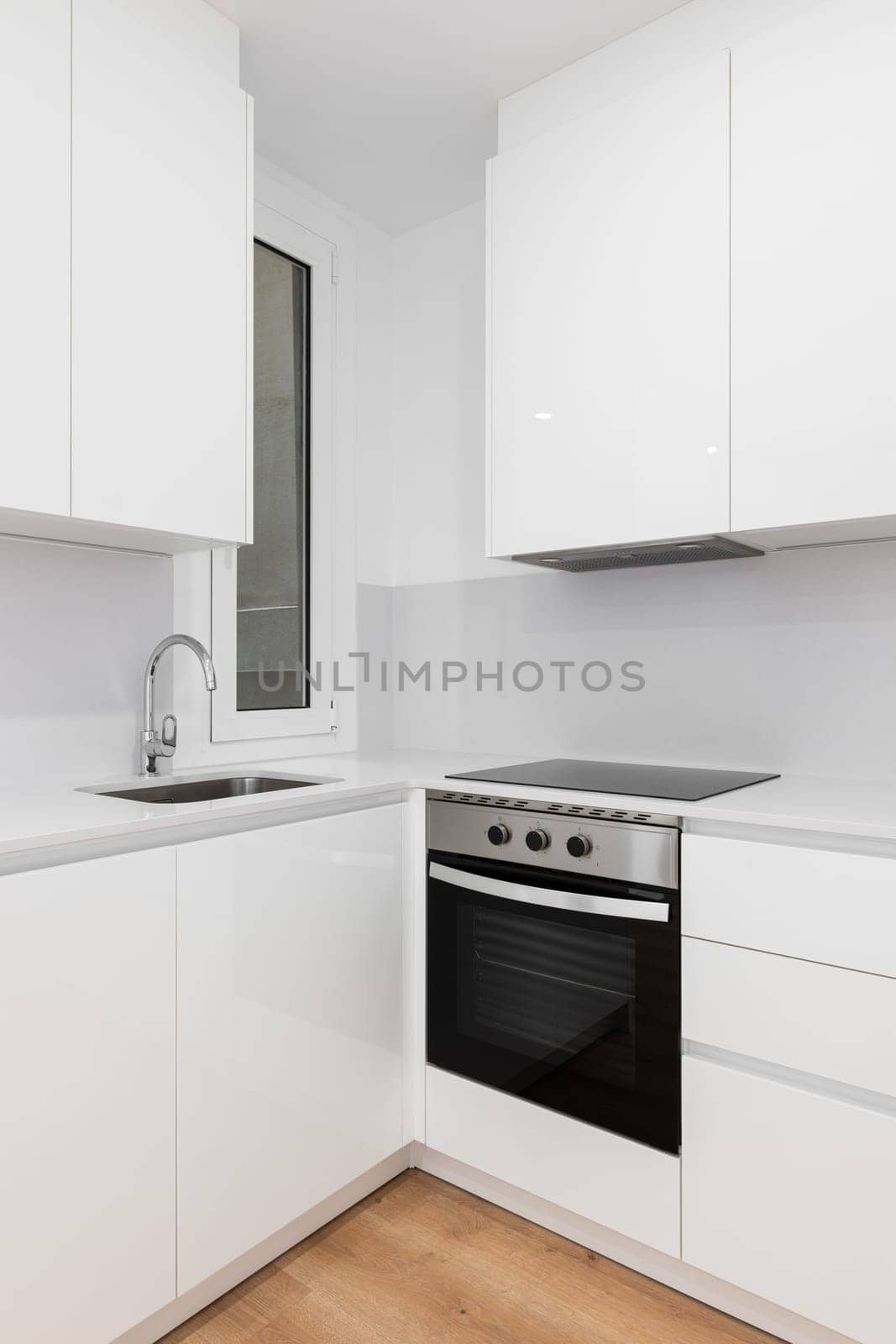 Modern white kitchen with sleek cabinets and a stylish black stove top oven by apavlin
