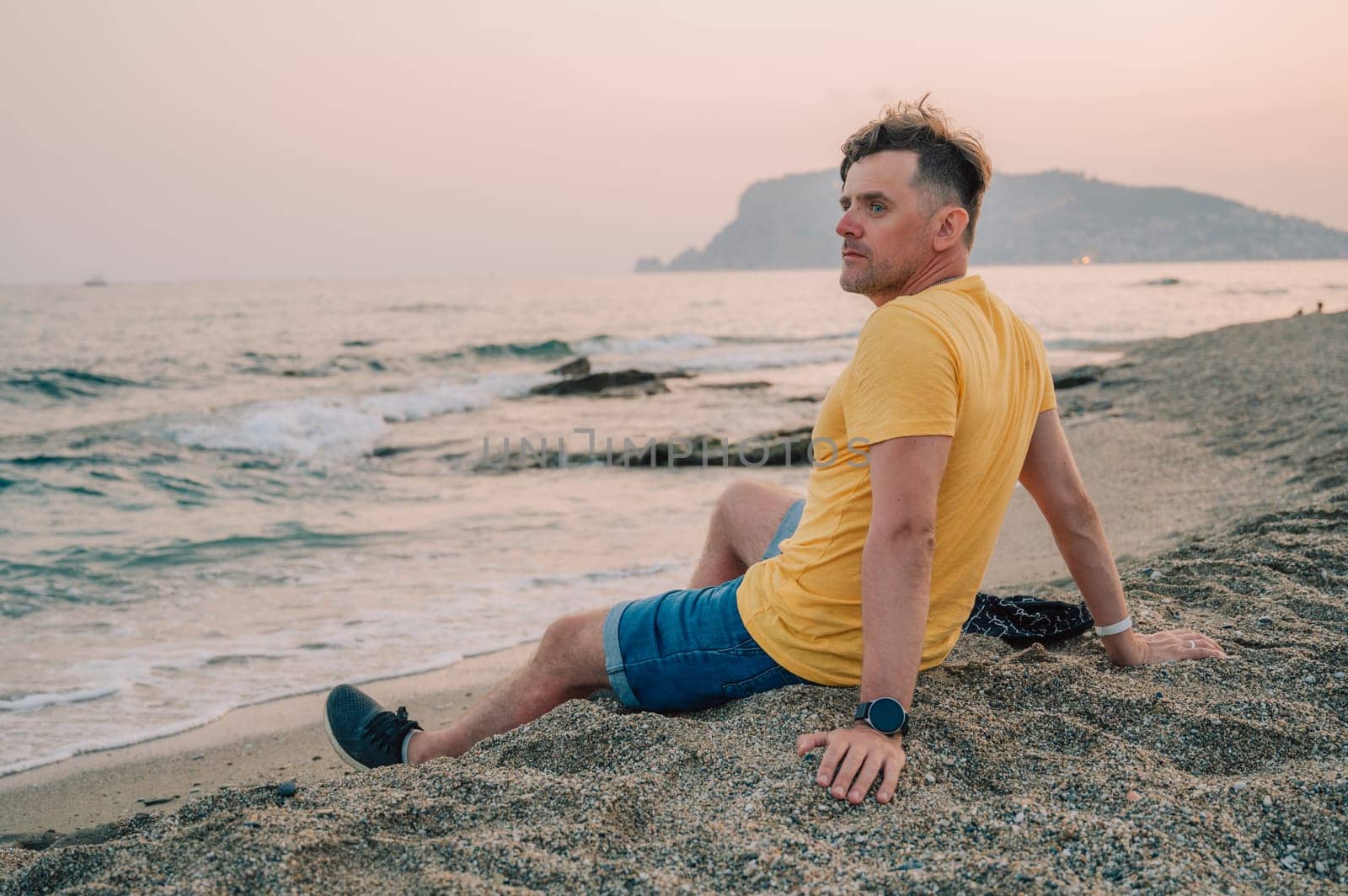 Man sits on the beach and looks at the sea in Alanya city, Turkey. Travelling or vacation concept