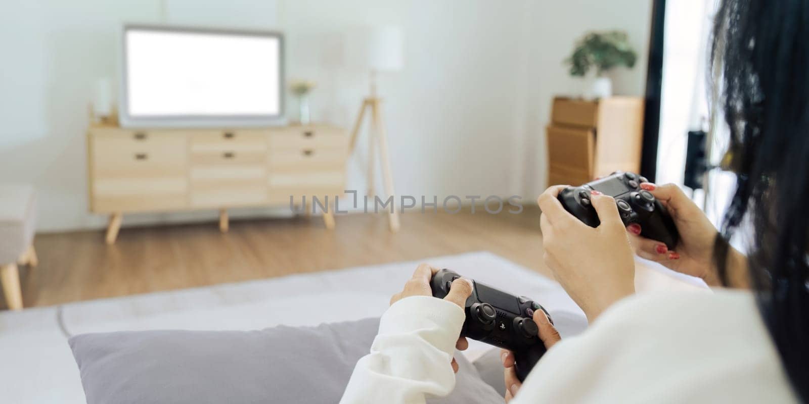 Asian beautiful lesbian gay couple enjoy play game together in Livingroom. Two female friend sit on sofa in living room, feel happy to play joystick game at home..