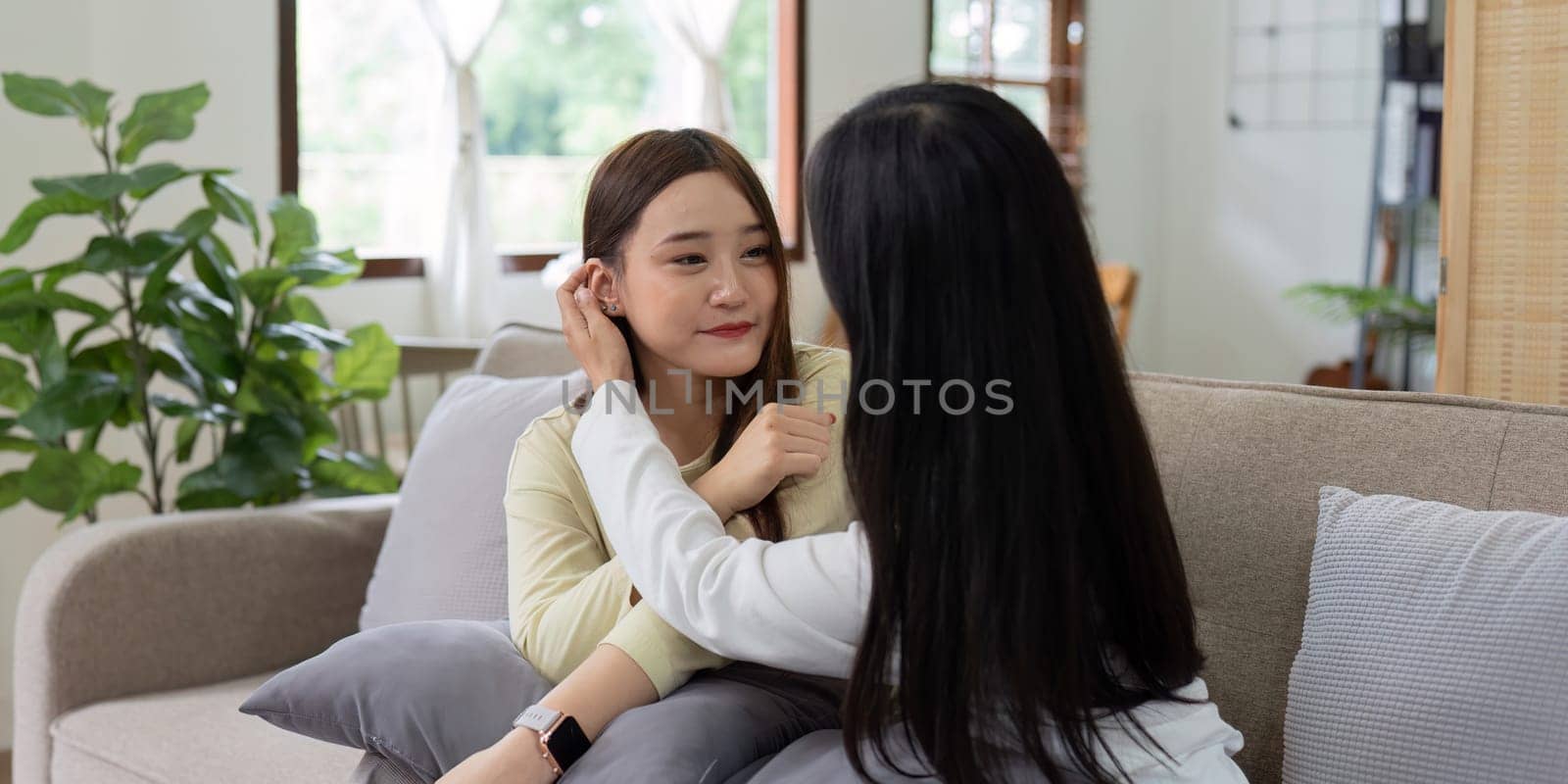 Loving LGBTQIA lesbian gay couple laughing together in Livingroom. Asian LGBTQIA lesbian gay couple laughed happy together while sitting on the sofa. Homosexual-LGBTQ concept..