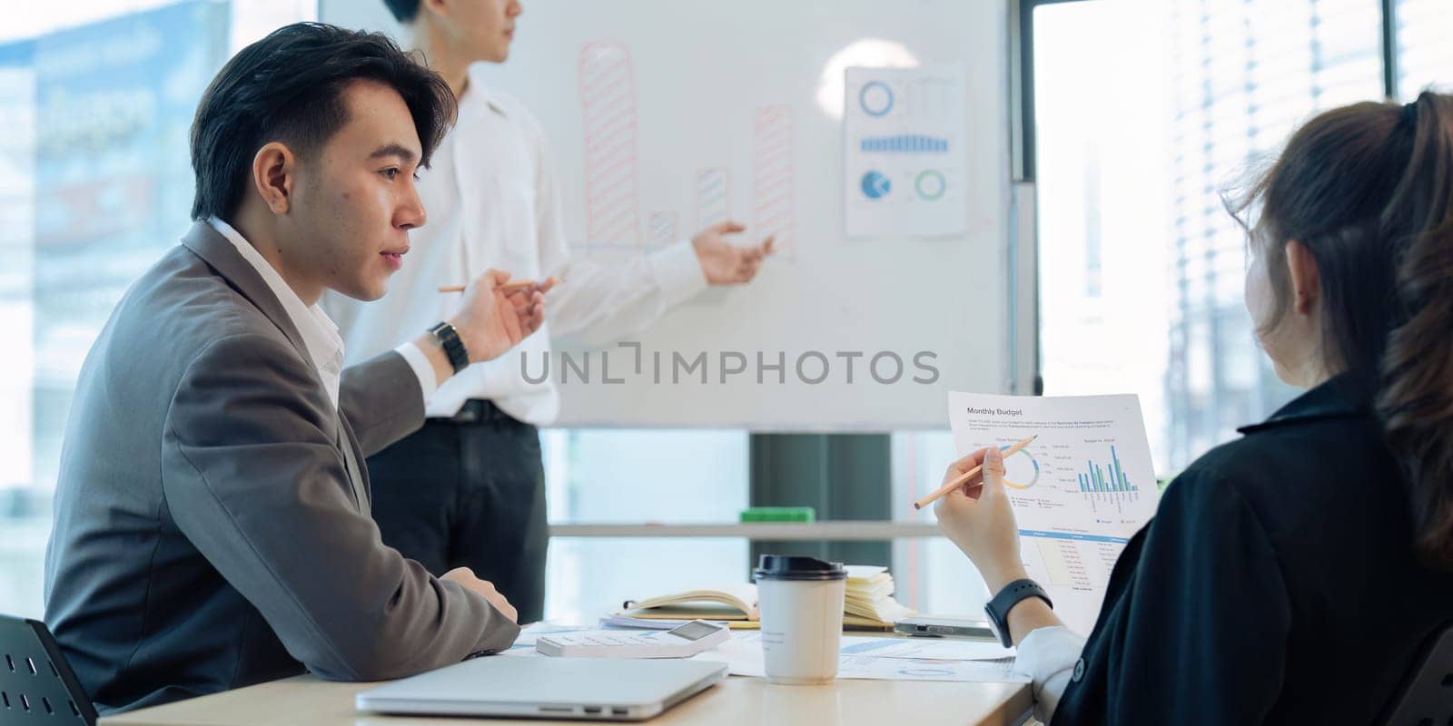 Young Business answering a colleague question during a presentation in boarding room by itchaznong