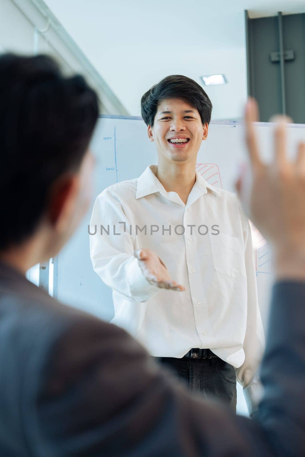 Young Business answering a colleague question during a presentation in boarding room by itchaznong