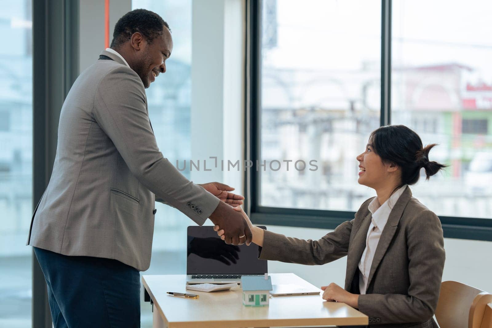 Real estate broker agent manager shaking hands with a client after successful agreement in the office. by itchaznong