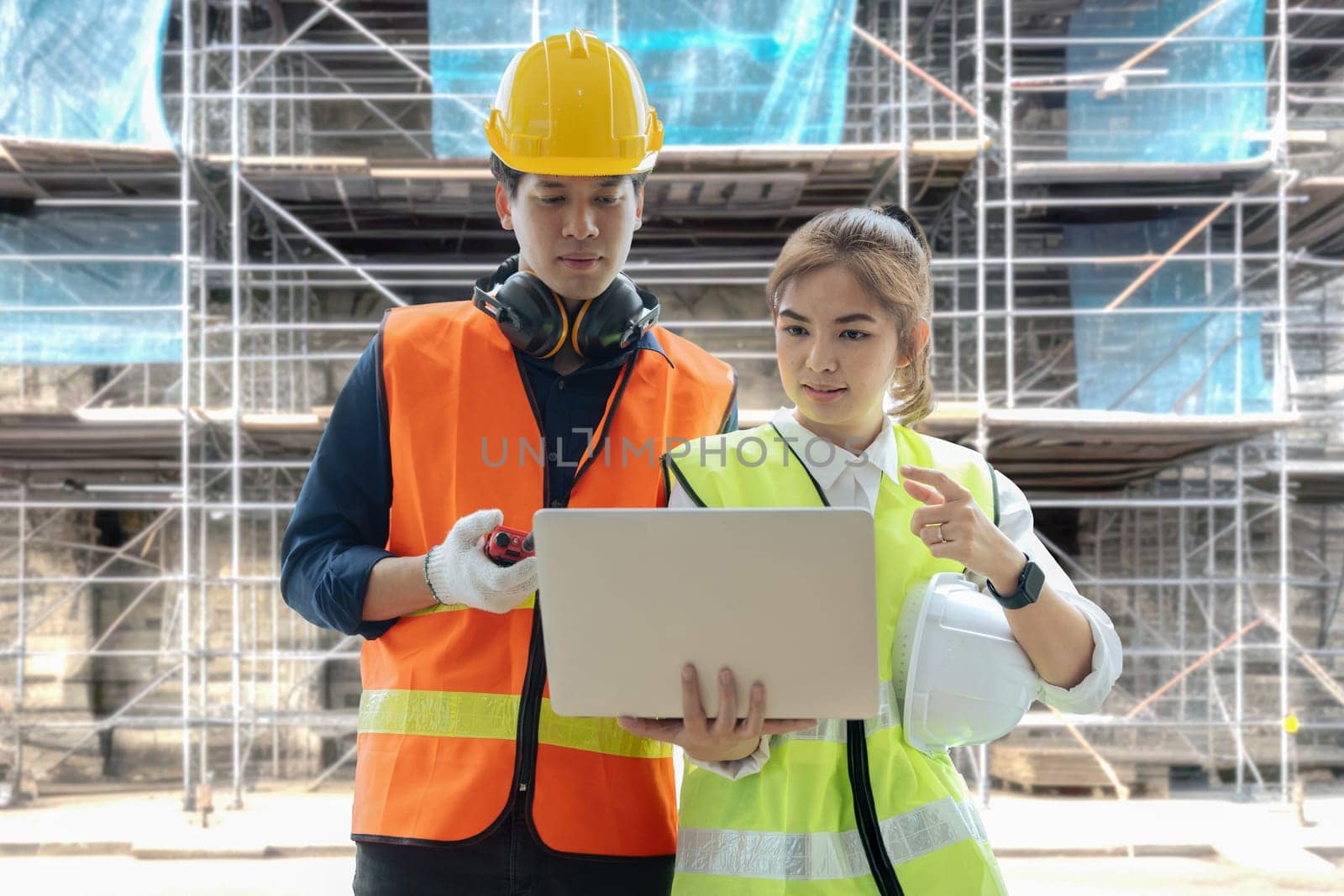 Two professional engineer and architect working on laptop together at construction site.