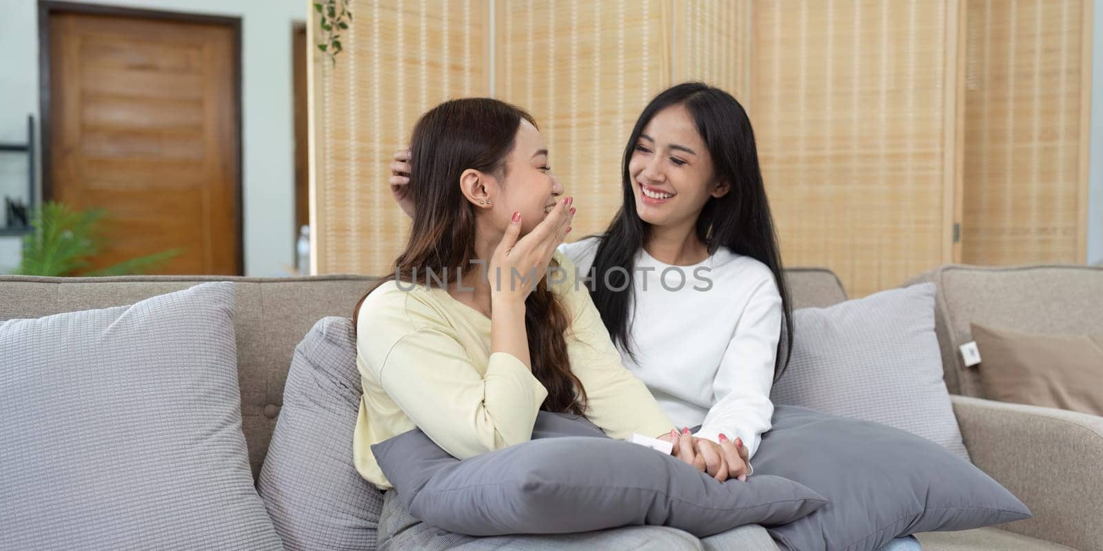 Loving LGBTQIA lesbian gay couple laughing together in Livingroom. Asian LGBTQIA lesbian gay couple laughed happy together while sitting on the sofa. Homosexual-LGBTQ concept..