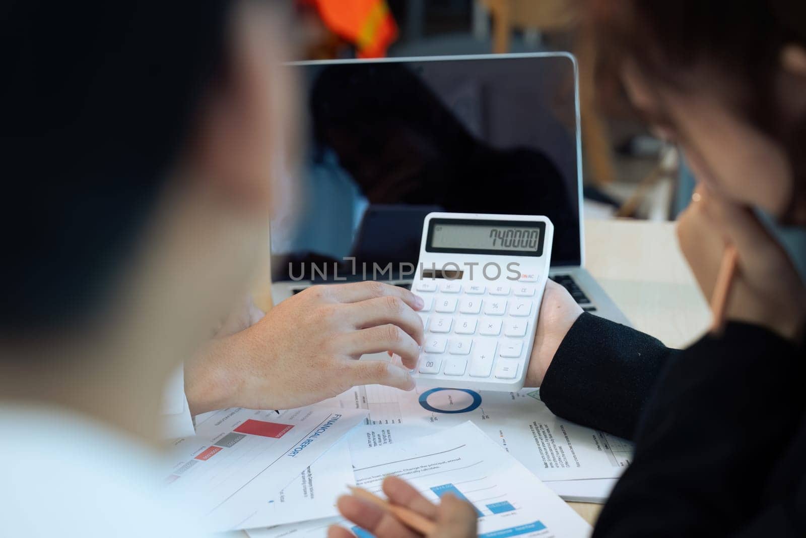 Businesswoman using a calculator to calculate numbers on a company's financial documents, analyzing historical financial data to plan how to grow the company. Financial concept. by itchaznong