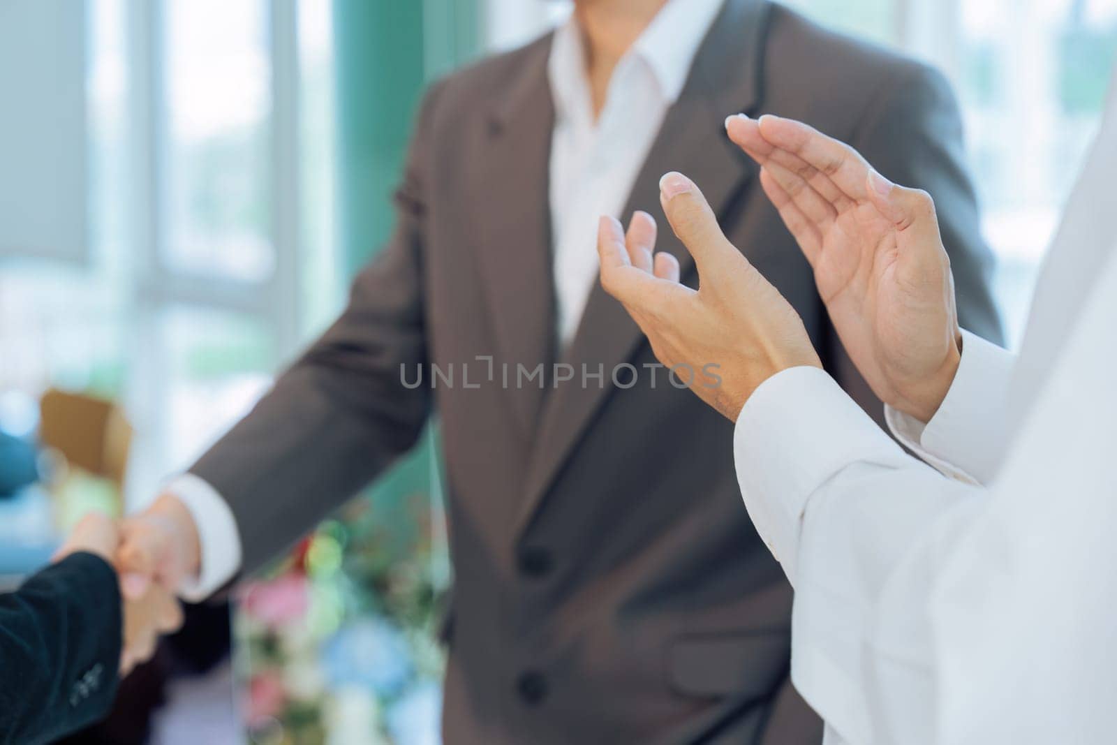 colleagues clapping hands while professional successful businesspeople in formal suit standing shaking hands greeting celebrating in company office.