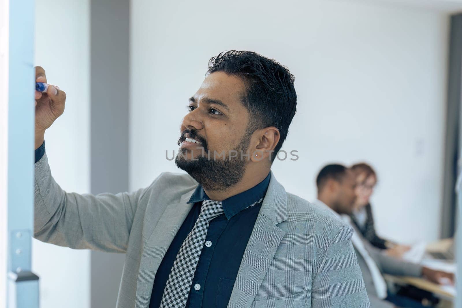 Indian businessman working and writing on the board while brainstorm in office.