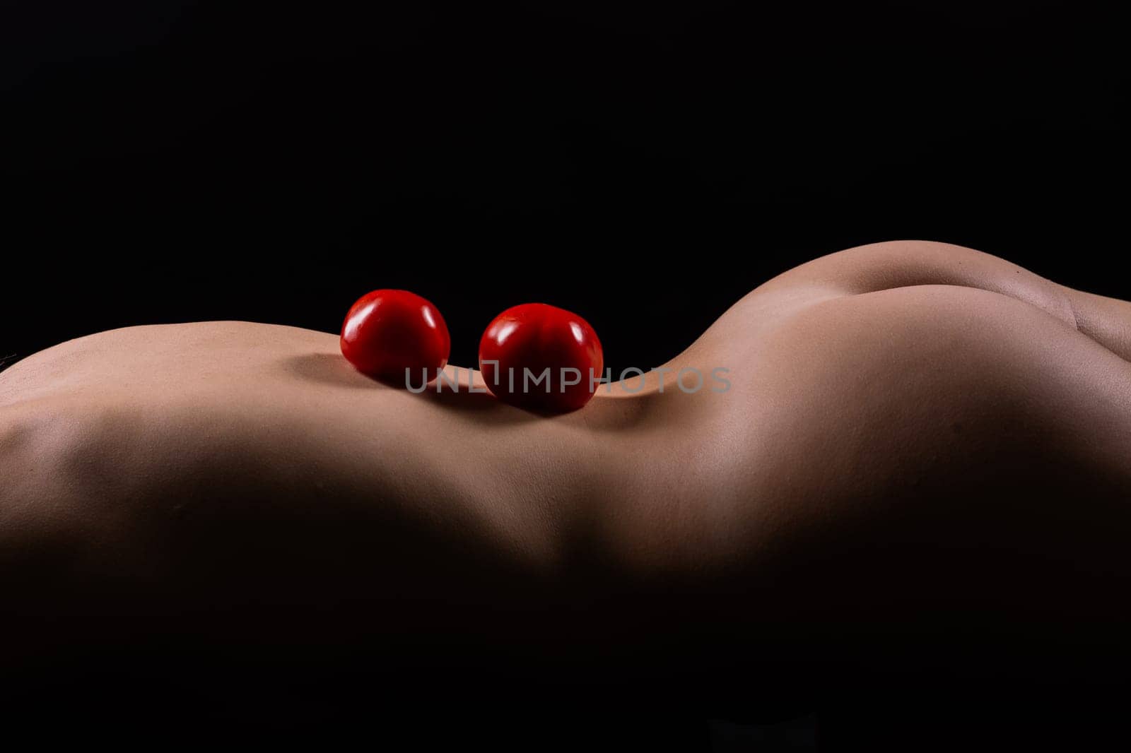 Nude woman with red apple on her back, dark background by Zelenin