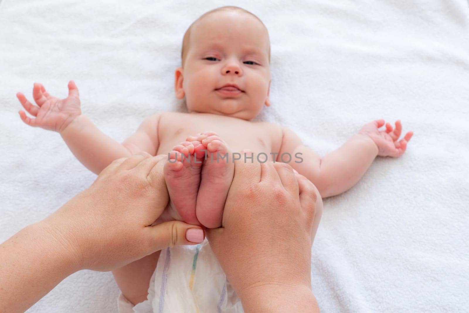 Mother's gentle hands massage baby's legs. Concept of natural constipation and colic solution