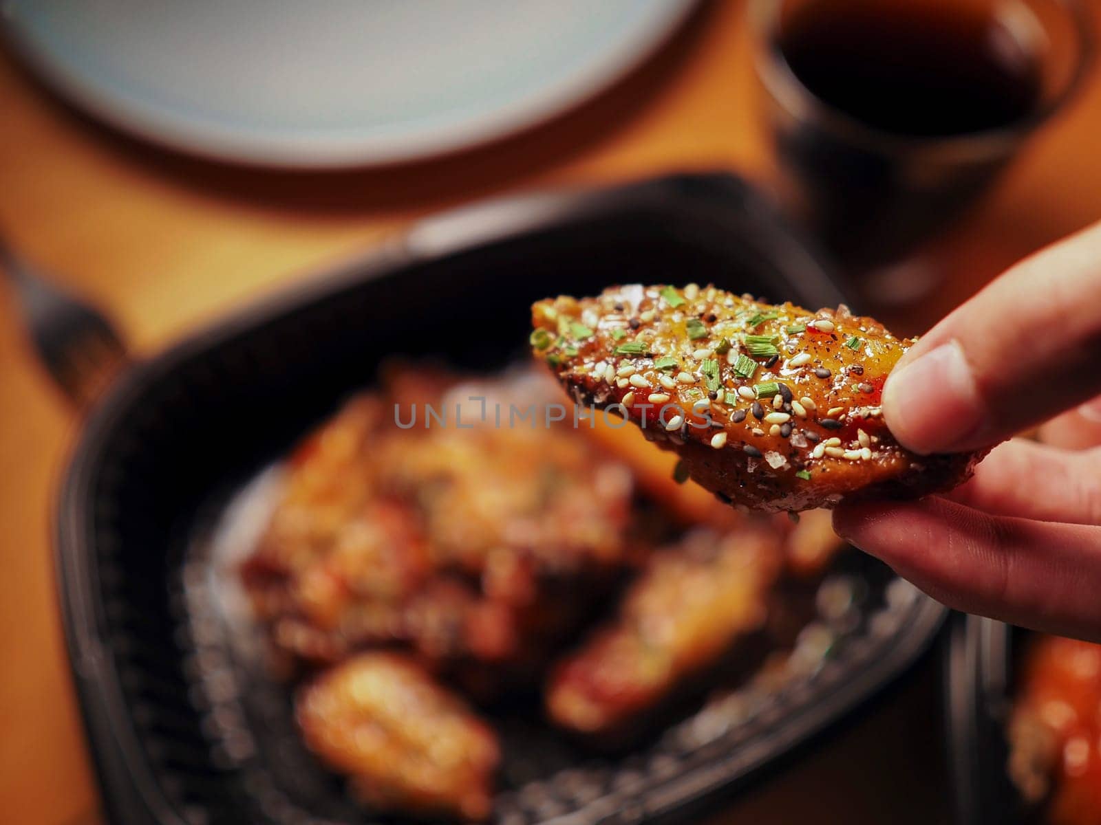 A man picking up a chicken wing in Korean style. Asian food. Delivery concept by ImagesRouges