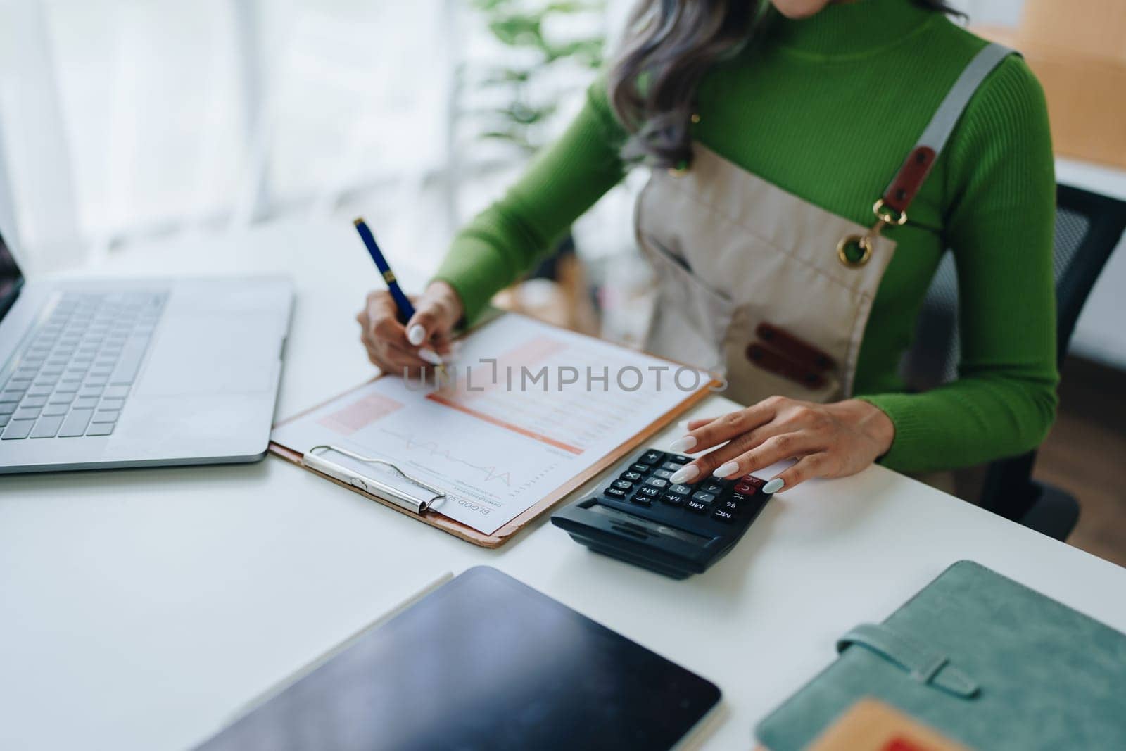 Small business, online business owner, young woman is using profit calculator and checking inventory.