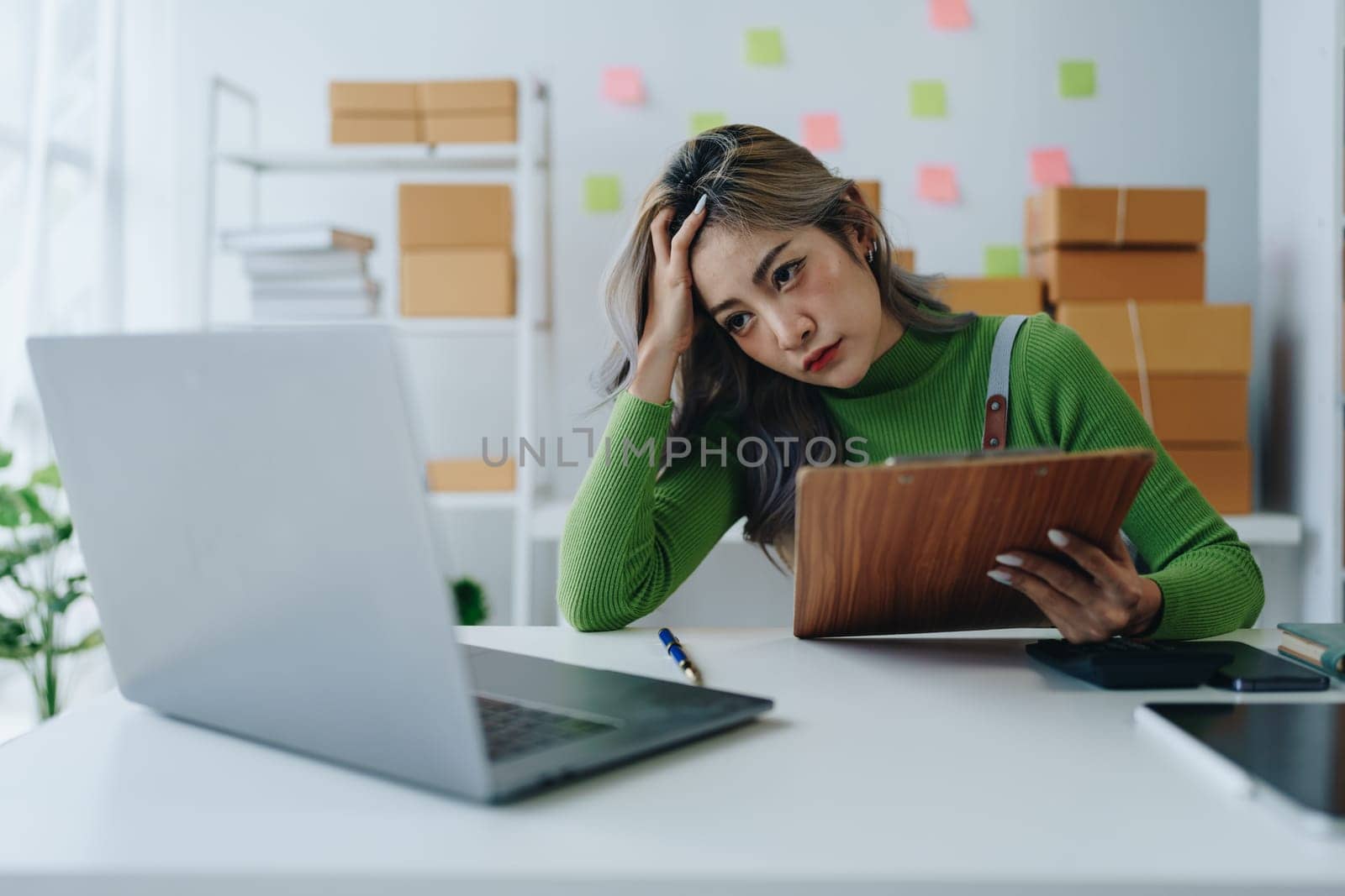 Starting small business entrepreneur of independent Asian woman showing her face worried about the sales of her business not reaching the target set. SME concepts.