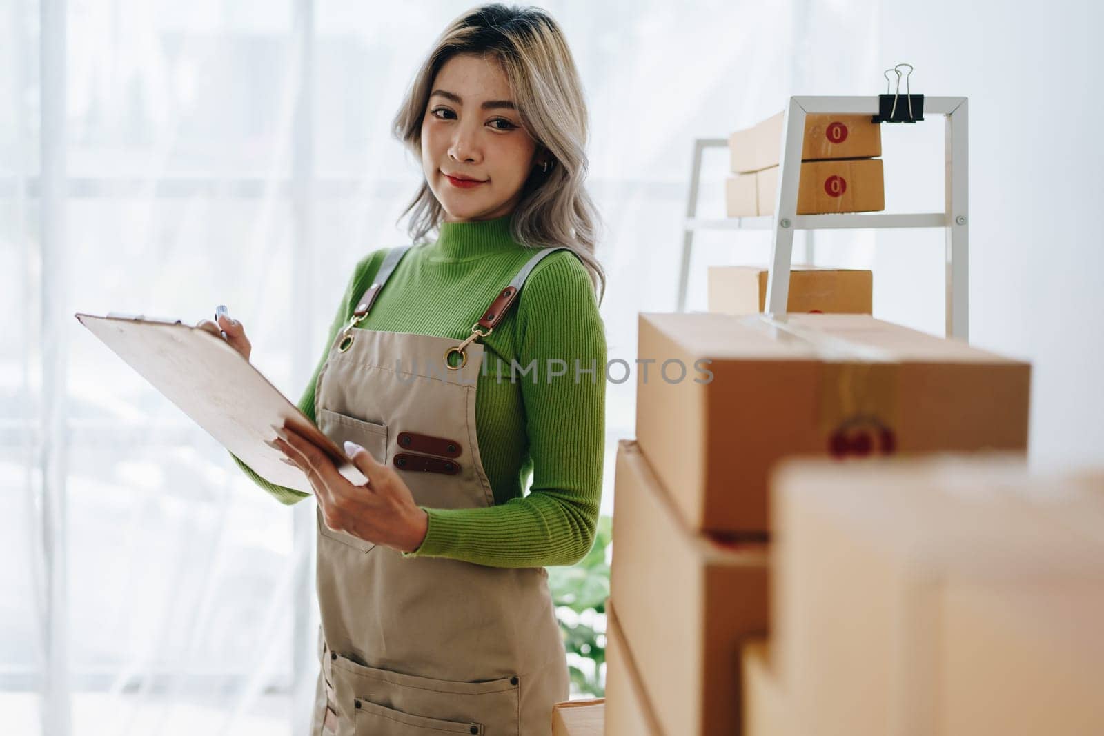 Starting small business entrepreneur of independent young Asian woman online seller is using computer and taking orders to pack products for delivery to customers. SME delivery concept.