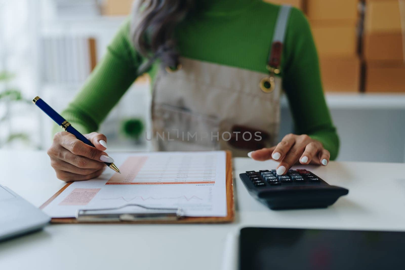 Small business, online business owner, young woman is using profit calculator and checking inventory.