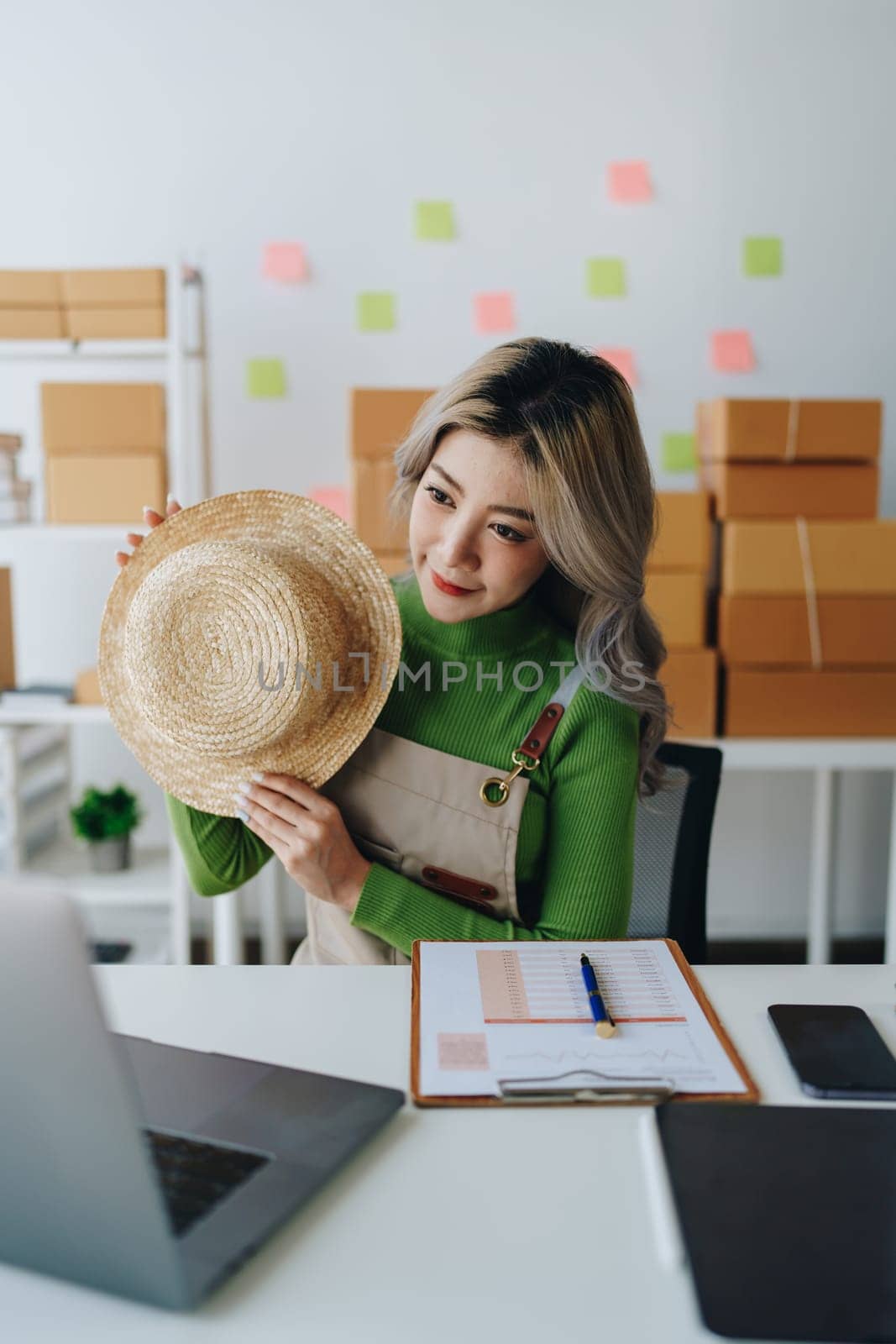 Starting small business entrepreneur of independent Asian female online seller talking on computer to video with a customer and packing products for delivery to the customer. SME delivery concept by Manastrong
