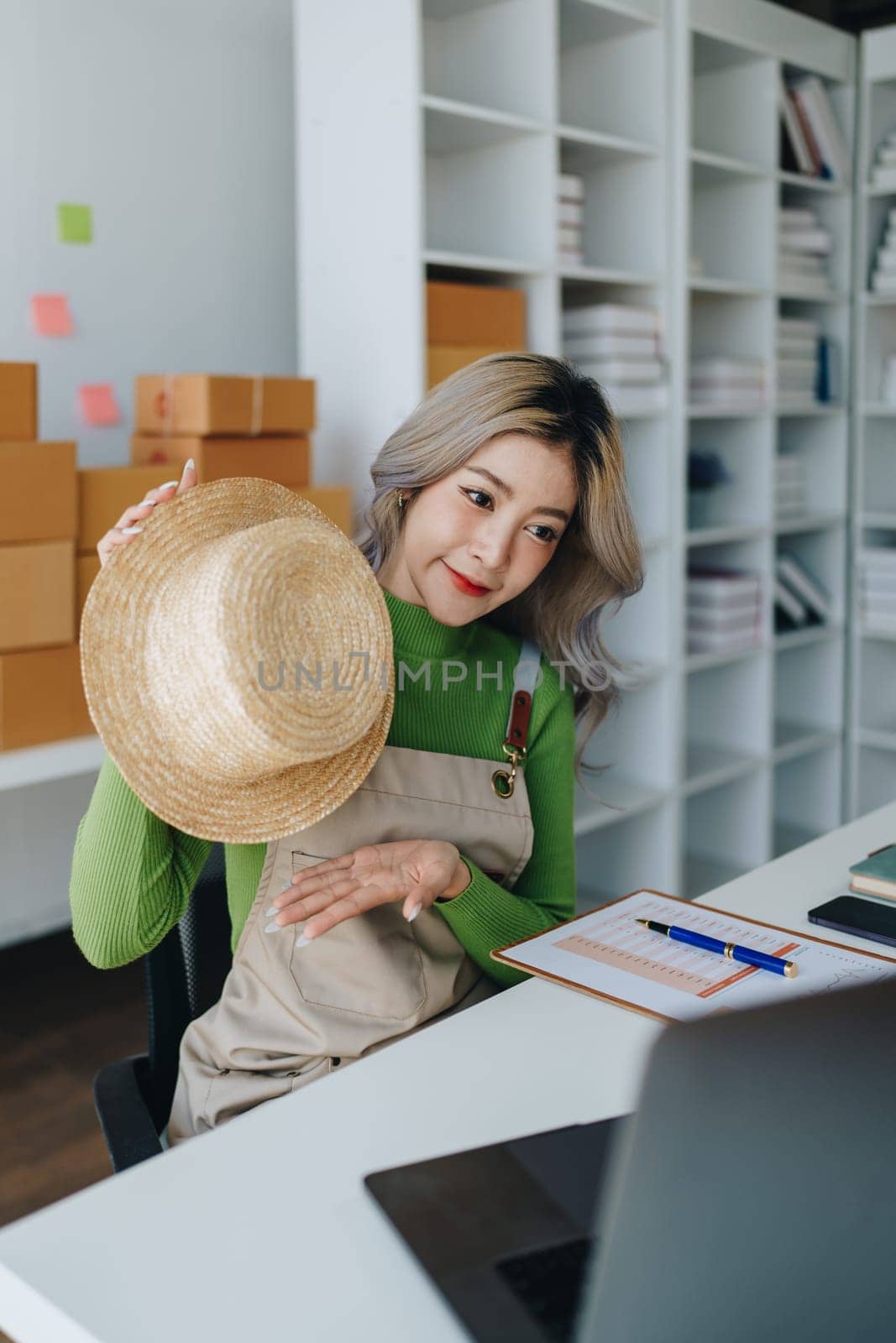 Starting small business entrepreneur of independent Asian female online seller talking on computer to video with a customer and packing products for delivery to the customer. SME delivery concept.