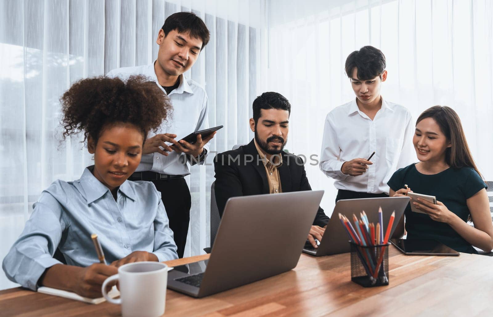 Happy diverse business people work together, discussing in corporate office. Professional and diversity teamwork discuss business plan on desk with laptop. Modern multicultural office worker. Concord